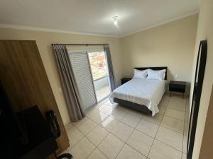 a bedroom with a bed and a sliding glass door at Apartamento Perto do balonismo Boituva com garagem coberta! in Boituva
