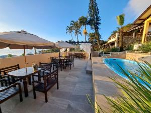 a patio with tables and umbrellas and a swimming pool at Pousada Vila do Navegante in Bombinhas
