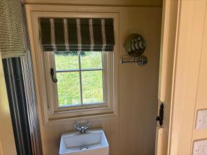 a bathroom with a sink and a window at Cosy Shepherd Hut in Kempsford +10 photos