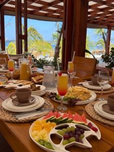 a table with plates of food and glasses of orange juice at KoKo Beach - Wooden Green House in Vila Praia Do Bilene