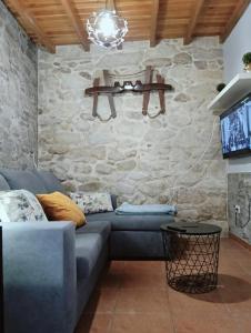 un soggiorno con divano blu e parete in pietra di Casa Consuelo a Sabardes