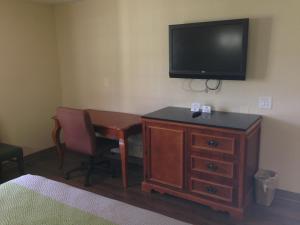 a room with a desk and a television on a wall at Red Carpet Inn - New Brunswick in New Brunswick
