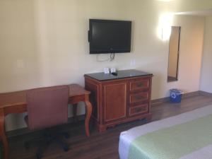 a hotel room with a desk and a television on the wall at Red Carpet Inn - New Brunswick in New Brunswick