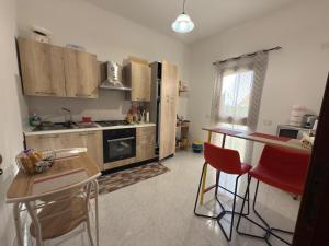 a kitchen with wooden cabinets and red chairs in it at Al Manzil in Locogrande
