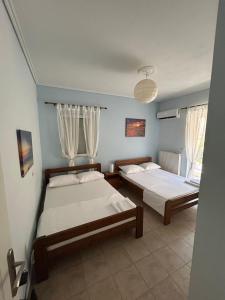 two beds in a room with two windows at The Big Blue in Gythio