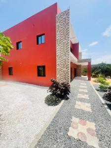 un edificio rojo con un camino delante de él en Villa Noflaye, en Déni Biram Ndao