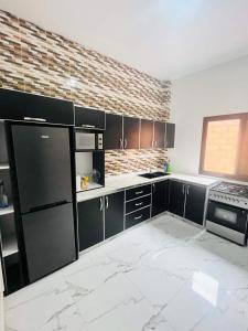 cocina con electrodomésticos negros y pared de ladrillo en Villa Noflaye, en Déni Biram Ndao