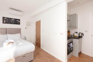 ロンドンにあるVillas Apart Hotelのベッドとキッチンのある白い寝室 +3枚の写真