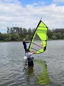 two people are holding a sail in the water at MARINASURF Baza Wypoczynkowa in Przeczyce