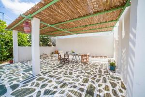 a patio with a table and chairs under a wooden roof at Family Home PortoKatapola in Katapola