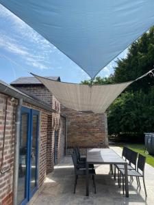 un patio con mesa y sillas bajo un techo en Maison des Fontainettes, en Les Andelys