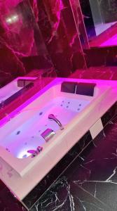 Una bañera con iluminación rosa en un baño. en Jacuzzi przy Plaży - Apartament Kołobrzeg, en Kołobrzeg