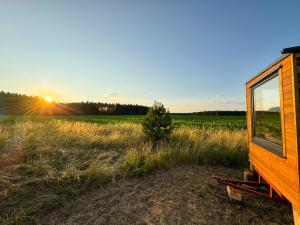 una casa en un campo con la puesta de sol en el fondo en Maringotka uprostřed ničeho, en Třemošná