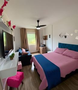 a bedroom with a pink and blue bed and a couch at BELO flat Cavalinho Branco-Aguas de Lindóia in Águas de Lindóia