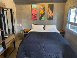 Una cama en una habitación con tres cuadros en la pared. en Moema Modern Studio, en São Paulo