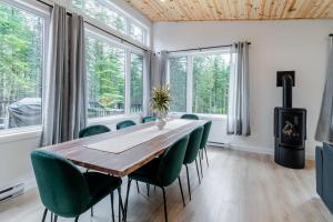 een eetkamer met een houten tafel en groene stoelen bij Villa Le Frigg spa swimming pool in Valcartier Station