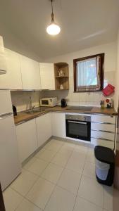 a kitchen with white cabinets and a sink and a microwave at Holiday House Gioia in Chia