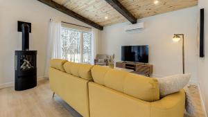 a yellow couch in a living room with a tv at Chalet Mirasol in Valcartier Station