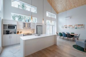een keuken met witte kasten en een tafel met stoelen bij Chalet Odin - SPA, PISCINE, SAUNA partagés in Valcartier Station