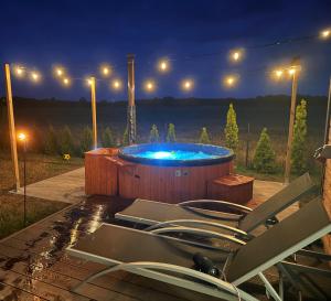 a hot tub with chairs in a backyard at night at Green-Point Podlasie in Drohiczyn