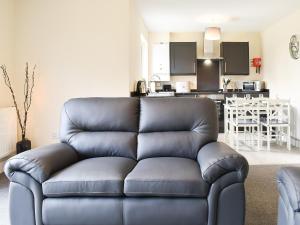 a leather couch in a living room with a kitchen at One Dorchester Drive - Uk32037 in Inglewhite