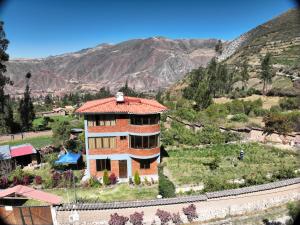 a house on a hill with mountains in the background at Casa de Campo Apu San Isidro in Urubamba