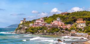 a group of houses on a hill next to the ocean at Villa della Contessa Cangini di Volterra con piscina e parco privato in Castiglioncello