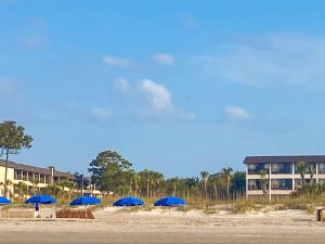 a group of blue umbrellas on a beach at Coastal King at Seaside Villas Ocean View in Hilton Head Island