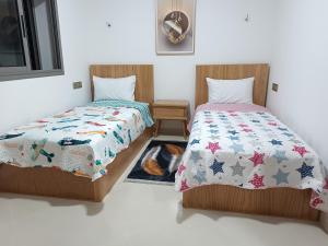 two beds in a room with a cat laying between them at BlueSea Studio's &Appart in Oualidia