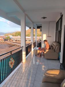 a person sitting on a couch on a balcony at Bajo Komodo Homestay in Komodo