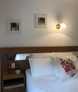 a bedroom with a bed with white sheets and pillows at Espaçoso Flat com Varanda no Cavalinho Branco in Águas de Lindóia