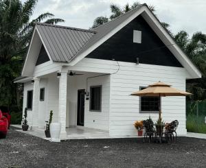une petite maison blanche avec une table et un parasol dans l'établissement Pondok Selesa Homestay, à Shah Alam