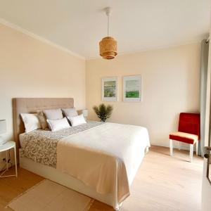 a bedroom with a large bed and a red chair at Foz do Arelho Sunset Sea Views Apartment in Foz do Arelho