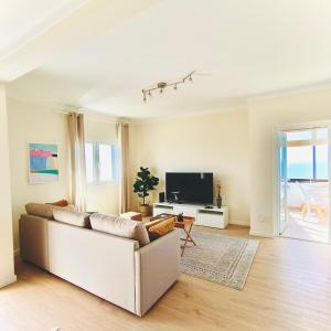 a living room with a couch and a tv at Foz do Arelho Sunset Sea Views Apartment in Foz do Arelho