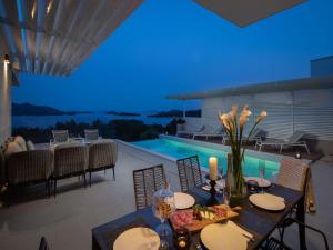 a dining room with a table and a swimming pool at Magnificent Murter Villa Villa Royal 4 Bedrooms Sea Views & Private Pool in Jezera +32 photos