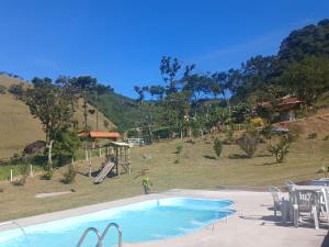 a swimming pool with a slide and a playground at Refúgio dos Moreiras in Monteiro Lobato