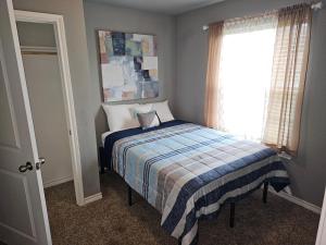 a bedroom with a bed with a plaid blanket and a window at Modern Home near Downtown Dallas in Lancaster