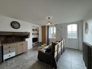 ein Wohnzimmer mit einer Couch und einer Uhr an der Wand in der Unterkunft Gîte paisible à Saint-Léon, proche nature et randonnées - FR-1-489-518 in Saint-Léon + 8 Fotos