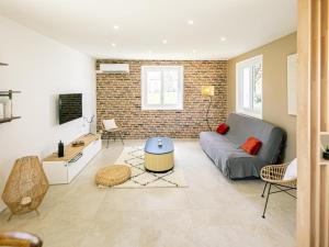 un soggiorno con un divano e un muro di mattoni di Gîte de charme avec spa, terrasse et grand jardin, au cœur des vignobles entre Moulins et Vichy - FR-1-489-507 a Saulcet
