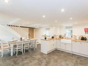 a kitchen with white cabinets and a table and chairs at Manor Cottage in Tideswell
