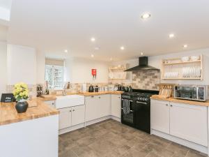 a kitchen with white cabinets and black appliances at Manor Cottage in Tideswell