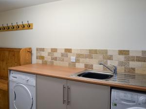 a kitchen with a sink and a washing machine at Manor Cottage in Tideswell +21 photos