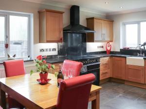 a kitchen with a wooden table with red chairs at Ty'n Rallt in Bodorgan