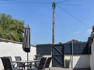 a table and chairs with an umbrella on a patio at No 12 Cottage in Mold +1 photo