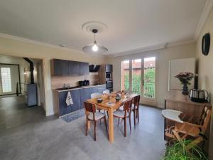una cucina e una sala da pranzo con tavolo e sedie di Gîte spacieux avec terrasse, cheminée, wifi et parking à Roanne - FR-1-496-337 a Roanne