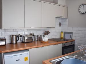 a kitchen with white cabinets and a counter top at No 12 Cottage in Mold