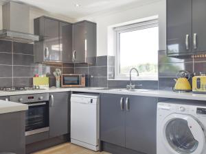 Una cocina con gabinetes grises y lavadora y secadora. en Coastal Soul - Uk43464, en Sandown