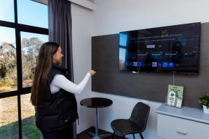 a woman standing in a room with a tv at Prospect Hotel Motel in Blacktown