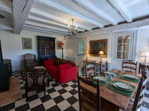 a living room with a table and a red couch at Charmante Maison de Campagne avec Piscine Chauffée en Charente - FR-1-653-278 in Abzac