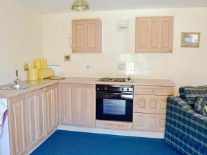 a kitchen with wooden cabinets and a stove top oven at Pig Sty Cottage - E1867 in Powerstock